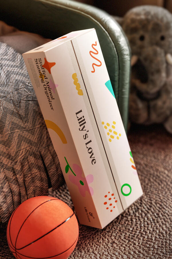 A Lilly's Love Stuffed Animal Standing Organizer box with playful, colorful graphics, placed next to a small basketball and a stuffed animal.