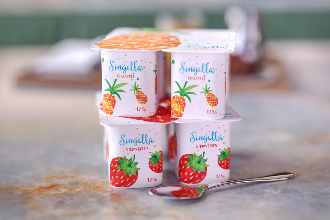 Eight Singella yogurt cups stacked in a four-by-four formation; four pineapple flavor on top and four strawberry flavor on the bottom, with a spoon nearby.