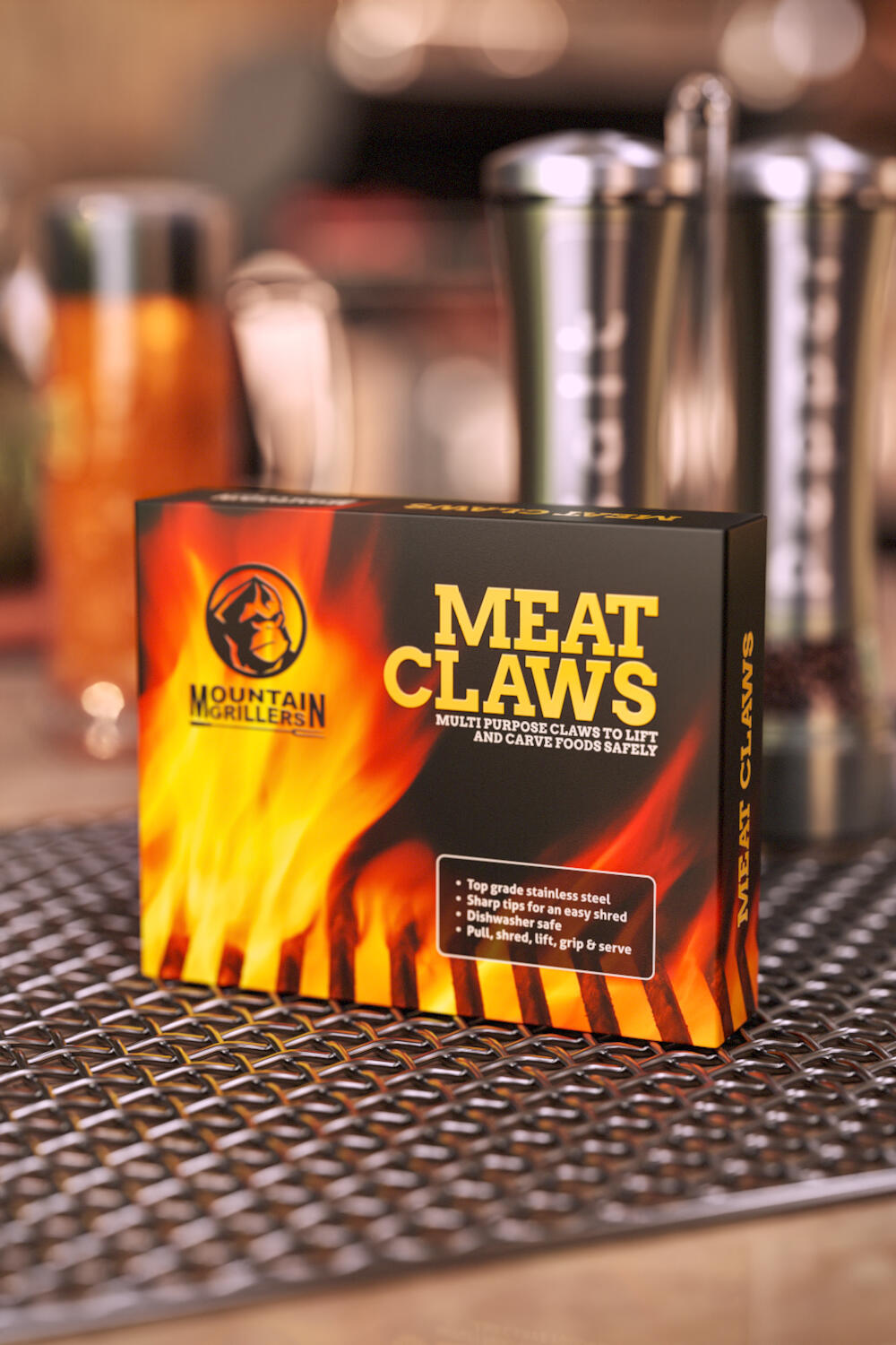 Mountain Grillers Meat Claws box with a flame design, set on a metal grill grate with barbecue accessories blurred in the background.